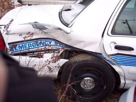 1991 Ford LTD Crown Victoria - A heavily damaged white vehicle, marked with 'EMERGENCY 911', sits outdoors with visible body damage.