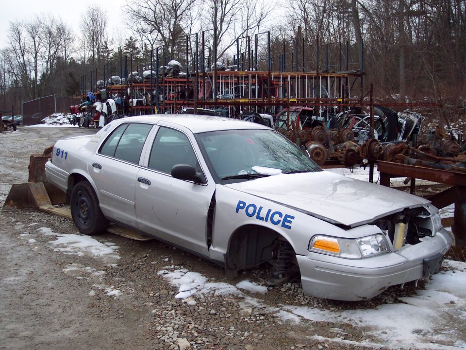 Silver police car with 'POLICE' on door and '911' on fender, missing wheels
