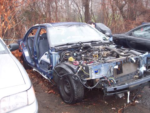 1991 Ford LTD Crown Victoria - A partially dismantled blue sedan sits outdoors next to another vehicle, with its engine compartment fully exposed.