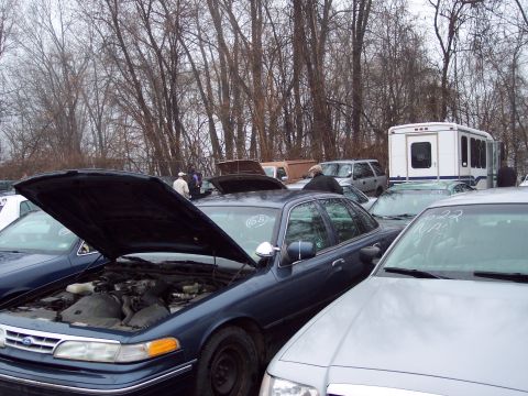 1991 Ford LTD Crown Victoria - A dark blue sedan, likely a 1992 model, is parked with its hood open at an outdoor auction.