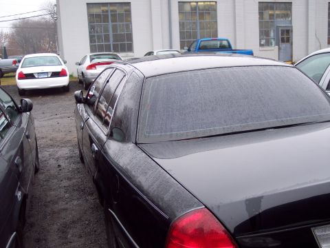 1991 Ford LTD Crown Victoria - A black Ford Crown Victoria is parked in a lot next to other vehicles, with a white Crown Victoria visible in the background.
