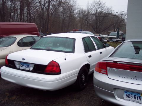 1991 Ford LTD Crown Victoria - Rear view of a white 1991 Ford Crown Victoria LTD police car, parked next to other vehicles.