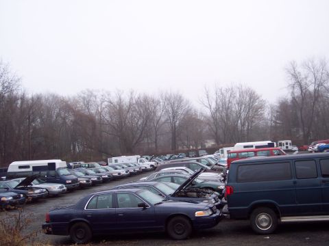 1991 Ford LTD Crown Victoria - A row of Ford Crown Victoria police cars and other vehicles are parked in an outdoor lot on a cloudy day.