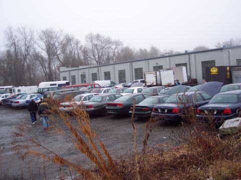 1991 Ford LTD Crown Victoria - A large group of vehicles are parked in an outdoor lot on an overcast day.