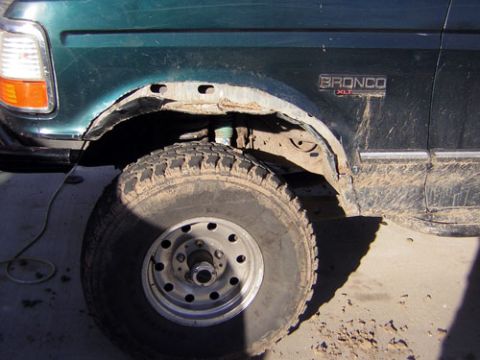 1995 Ford Bronco - The fender of a green Ford Bronco XLT shows significant rust damage around the wheel well.