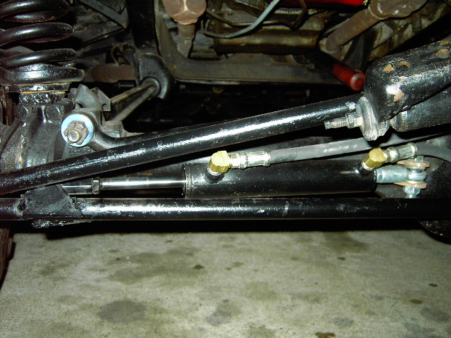 Close-up of black steering linkage and suspension parts, including a shock absorber and tie rod ends