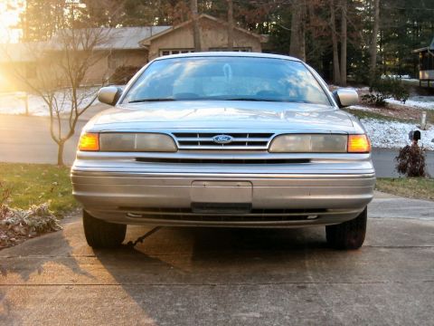 1985 Ford LTD Crown Victoria - The front grille and headlights of a silver sedan are visible in this daytime shot.