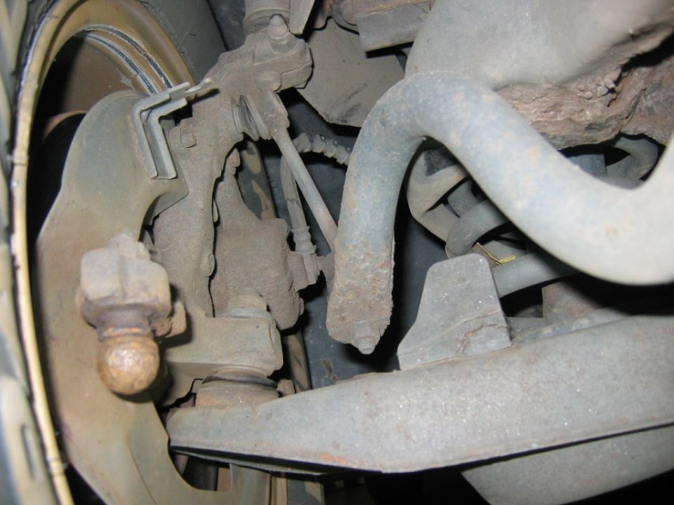 Close-up of rusty suspension parts, including a ball joint and sway bar
