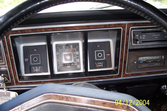 Dashboard gauges, radio, and steering wheel of an older vehicle