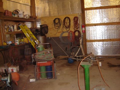 1992 Ford Bronco - Interior of a workshop filled with various tools and equipment, including welding gear and an air compressor.