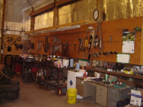 1992 Ford Bronco - A cluttered workshop scene features tools organized on a pegboard wall, a calendar, and various workbenches.
