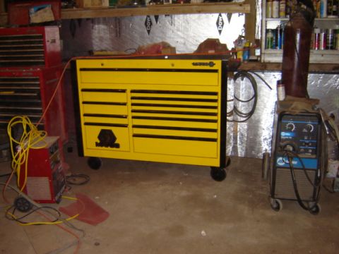 1992 Ford Bronco - A yellow rolling tool chest is positioned next to a Miller welding machine in a workshop.