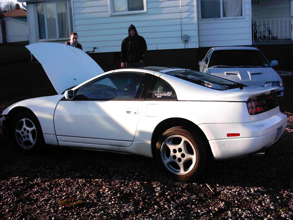 White Nissan 300ZX coupe with hood open and front bumper removed on a gravel driveway