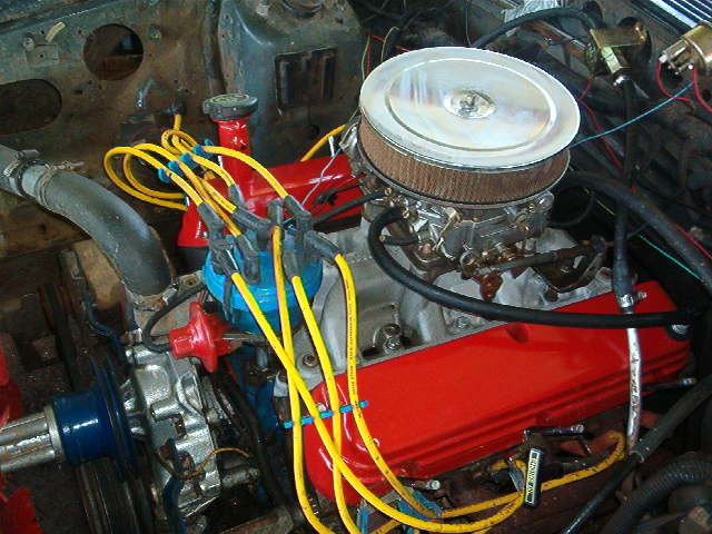Freshly rebuilt red V8 with chrome air cleaner and yellow plug wires in an engine bay