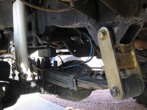 1994 Ford Bronco - Close-up view of the rear suspension system of a vehicle, showing leaf springs and a shock absorber.
