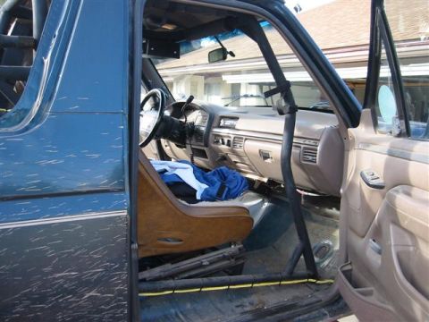 1994 Ford Bronco - Interior view of a blue Ford Bronco with tan upholstery and a visible roll cage.