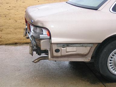 1999 Ford Crown Victoria - Rear view of a 1999 Ford Crown Victoria with significant damage to the bumper and quarter panel.