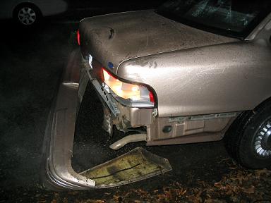 1999 Ford Crown Victoria - Rear damage to a 1999 Ford Crown Victoria, showing a detached bumper and cracked taillight.