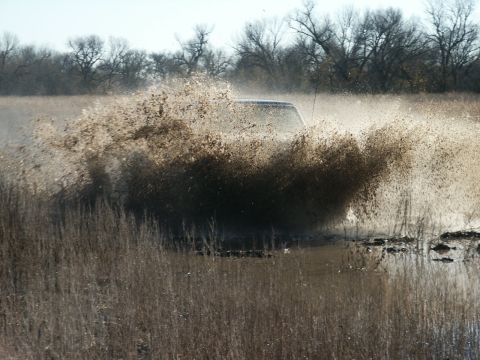 1991 Ford Bronco - A truck blasts through a flooded marsh, throwing a huge fan of muddy water and dead reeds so high that only its roofline and windshield are…