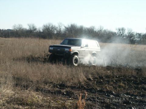 1991 Ford Bronco - This 1991 Ford Bronco is captured mid-action, navigating a field and creating a dust cloud.