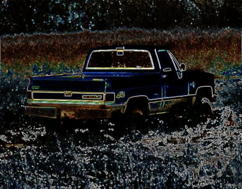 1991 Ford Bronco - A dark blue pickup truck sits in a field of tall grass, its body lines suggesting an 1980s Chevrolet model.