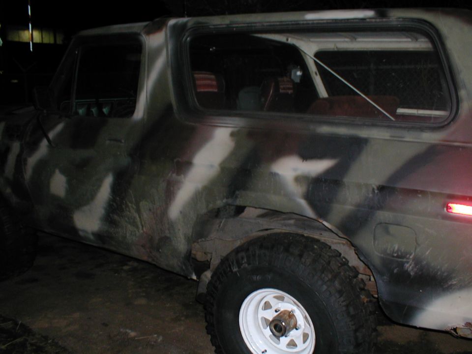 side view of a camouflaged SUV with white rims