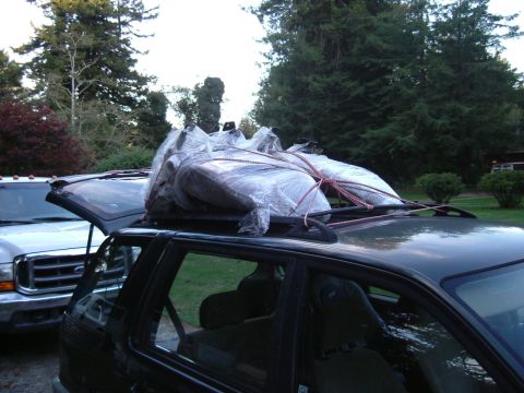 1993 Ford Bronco - Two vehicles are parked outside, one carrying wrapped items on its roof rack.