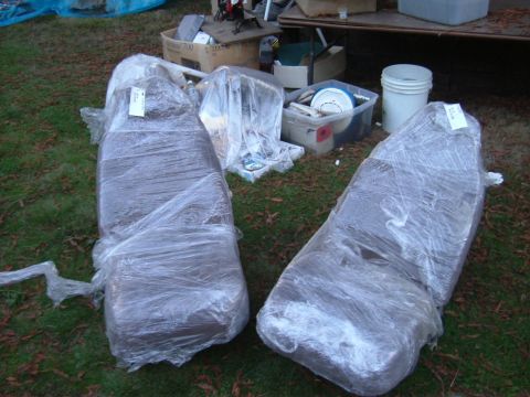 1993 Ford Bronco - Two car seats are wrapped in plastic and placed on the grass outdoors, with various storage containers nearby.
