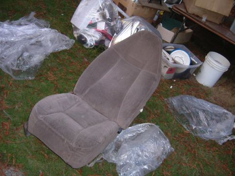 1993 Ford Bronco - A single car seat sits outdoors amidst various discarded items and containers.