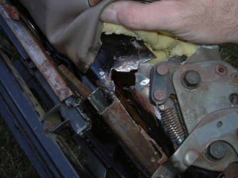 1993 Ford Bronco - The internal mechanism of a car seat is visible, showing rust and damage to the frame.