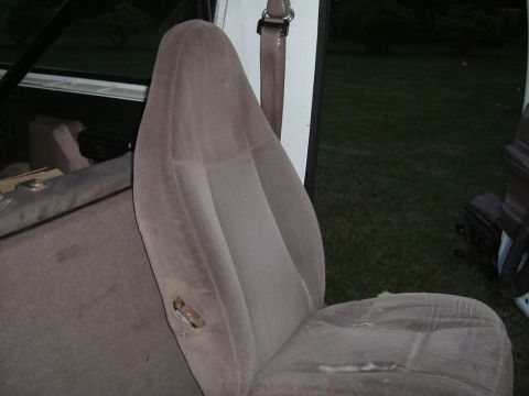 1993 Ford Bronco - The interior of a vehicle shows worn fabric on the seats, with visible damage on the side of the driver's seat.