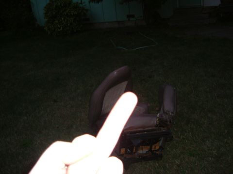 1993 Ford Bronco - A detached car seat sits on the grass in a yard, with a hand obscuring part of the view.