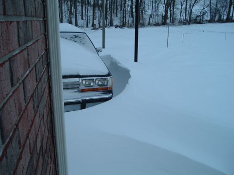 1995 Mercury Grand Marquis - A 1995 Mercury Grand Marquis is partially visible, buried in snow, with only the front grille and headlights showing.