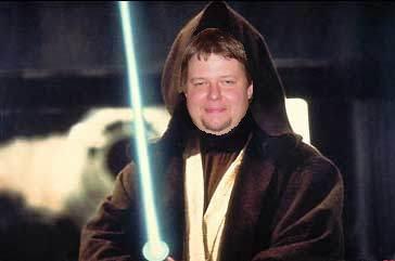 1995 Ford Bronco - A man dressed as a Jedi Knight holds a blue lightsaber, with a blurred background.