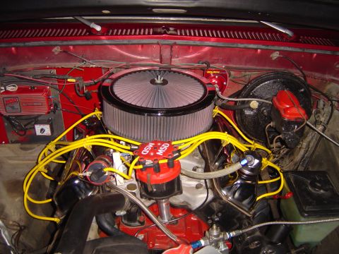 1978 Ford Bronco - Engine bay of a red truck looking down on a V8 with a red block, chrome-lipped round air cleaner, red MSD distributor cap and yellow spark…