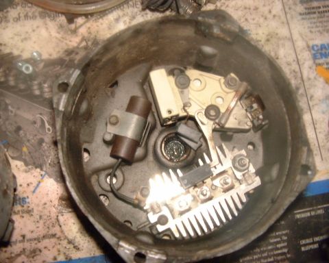 1985 Ford F-150 - The internal components of a disassembled automotive alternator are visible, including the voltage regulator and rectifier assembly.