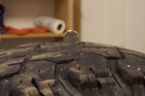 1987 Ford Bronco - A quarter is balanced on the tread of a tire, with a shelf visible in the background.