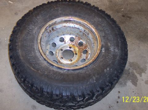 1987 Ford Bronco - A close-up of a single tire and rim, showing rust on the metal wheel.