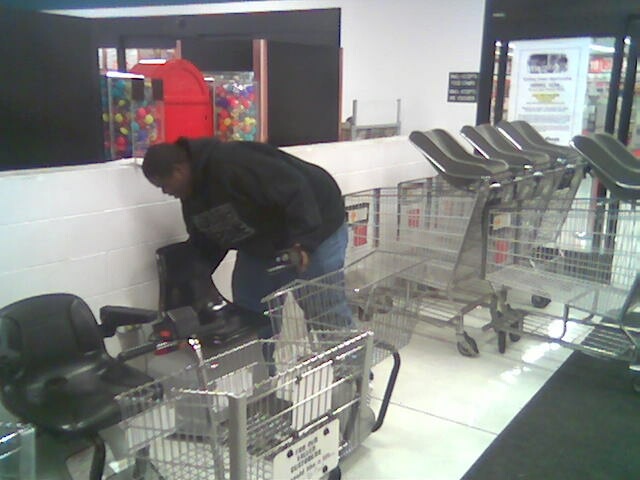 Shopping carts lined up in a store aisle with a person bending over one