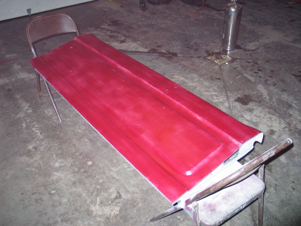 Red tailgate resting on sawhorses in a garage