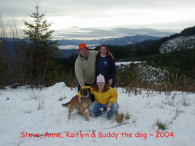 Family of three with a tan dog posing in snow on a mountain overlook, labeled 2004