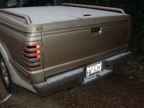 1993 Ford Taurus - Pickup truck rear with bed cover and Texas license plate, lightly dusted with snow.