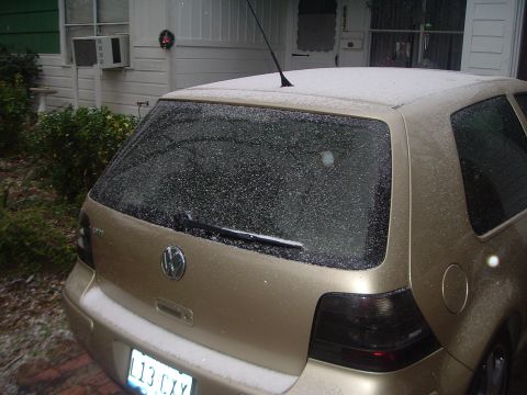 1993 Ford Taurus - A gold Volkswagen Golf is parked outside a house during a snowfall.