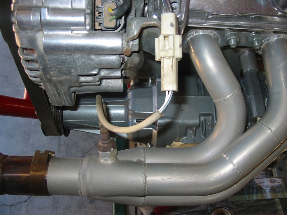 Engine exhaust manifold with exhaust gas sensor and alternator