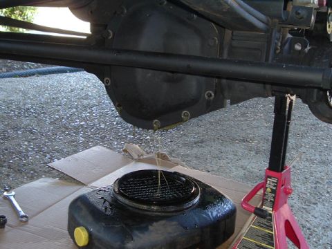 1989 Ford Bronco - Differential oil is being drained into a pan, with a SuperMotors logo visible in the lower right corner.