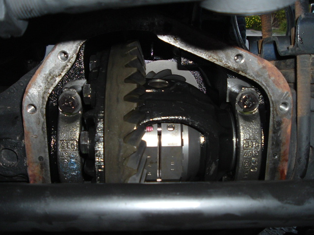 Open rear differential with cover off showing ring and pinion gears coated in oil