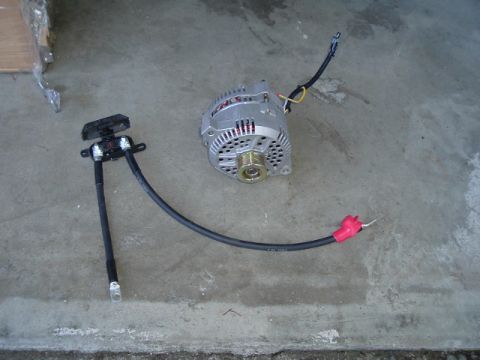 1989 Ford Bronco - An alternator and its associated wiring harness are laid out on a concrete surface.