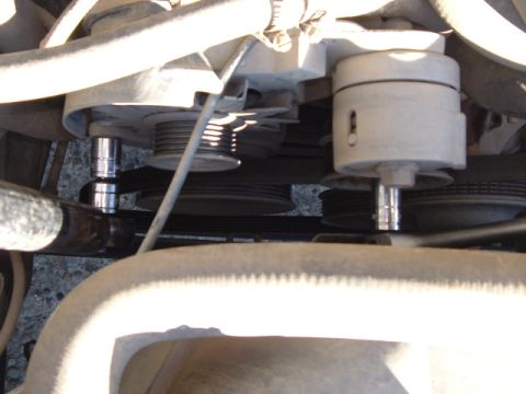 1989 Ford Bronco - Close-up view of an alternator installation, showing a socket wrench engaged with the pulley bolt.