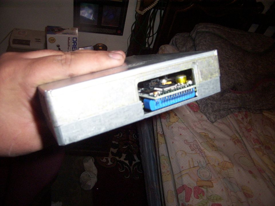 hand holding silver engine control unit with blue connector