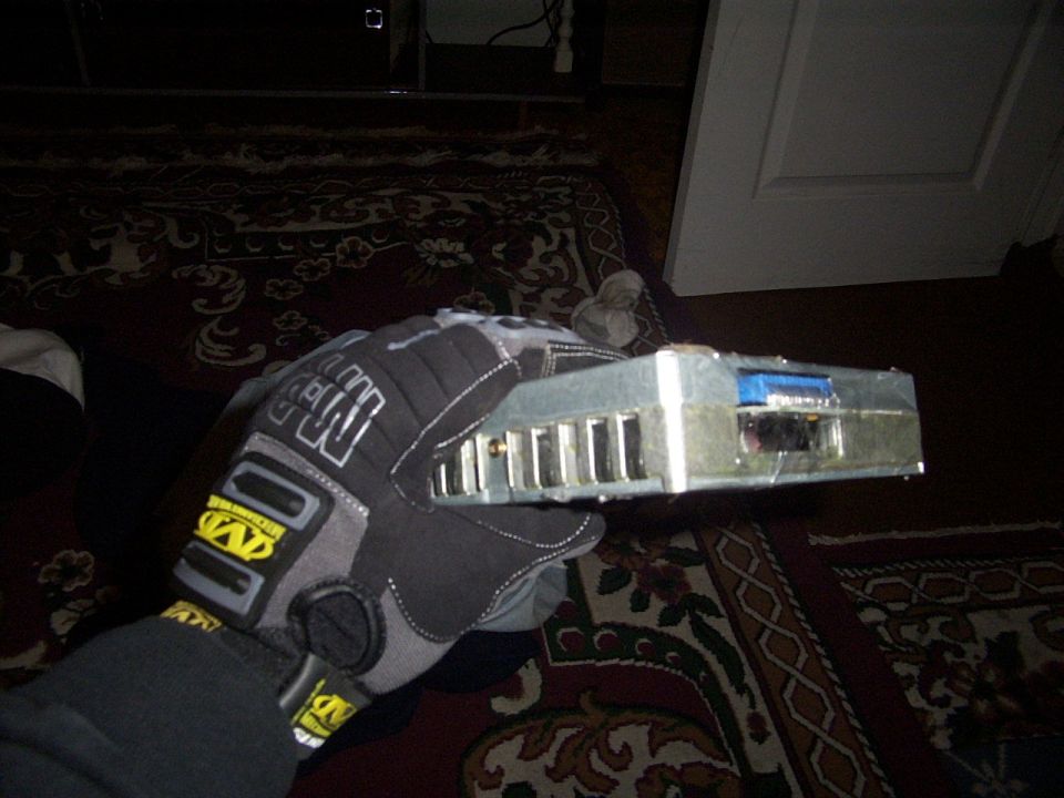 Gloved hand holding a silver electronic component with multiple ports